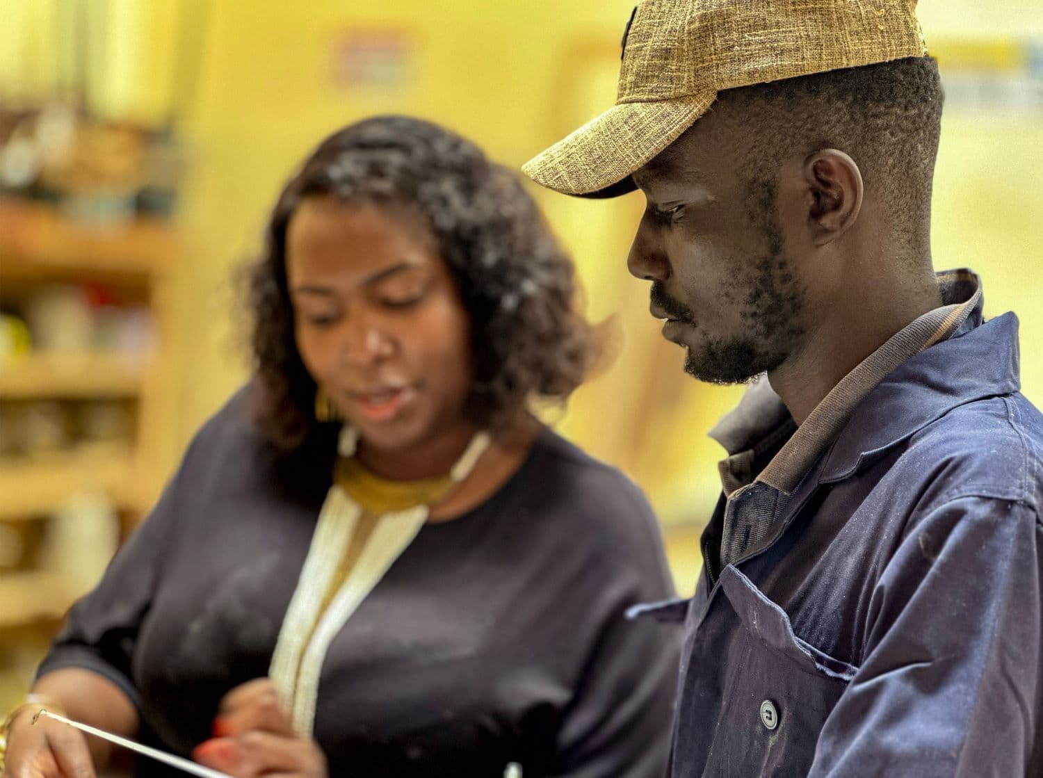 Emily Wangui giving a one of the workers furniture instructions from a client file at the workshop of Furniture Zoo in Nairobi, Kenya